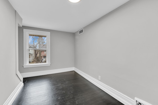 spare room featuring baseboards, visible vents, and dark wood finished floors