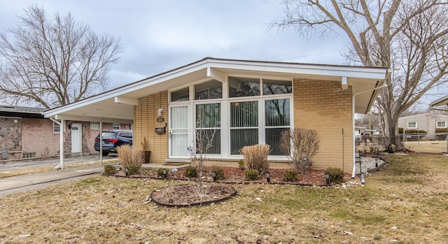 view of front facade with an attached carport, brick siding, fence, driveway, and a front yard