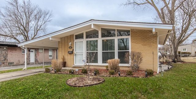 mid-century home with brick siding, fence, driveway, and a front lawn