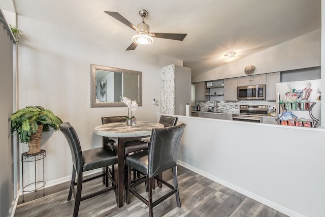 dining room featuring ceiling fan, baseboards, vaulted ceiling, and dark wood-style flooring