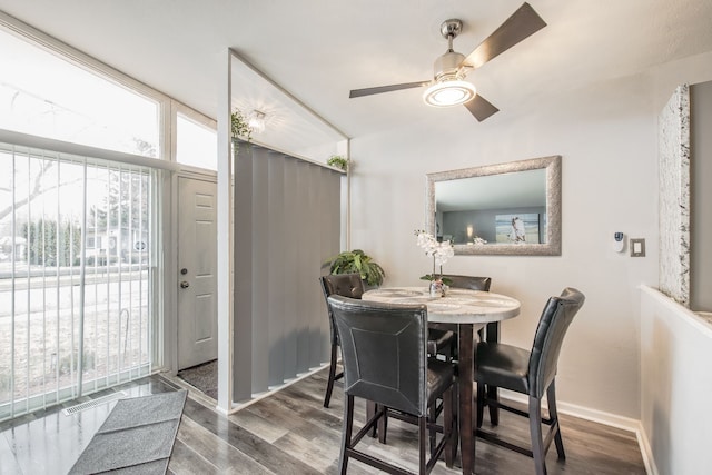 dining area with wood finished floors, a ceiling fan, and baseboards