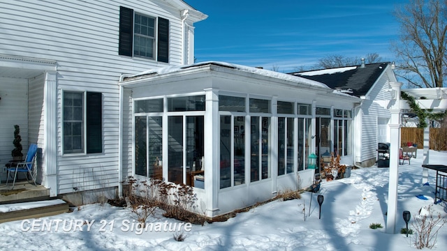 view of snowy exterior with a sunroom