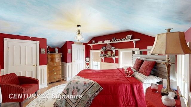 bedroom featuring vaulted ceiling, a wainscoted wall, and wood finished floors