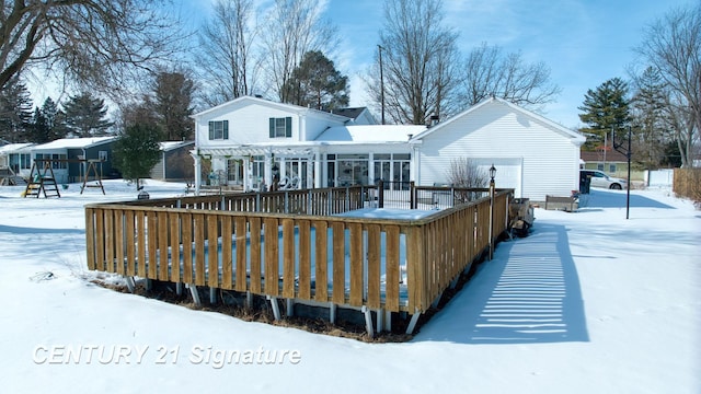 snow covered house with a deck and an attached garage