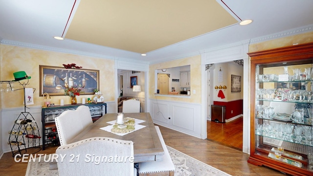 dining area featuring ornamental molding, wainscoting, and wood finished floors