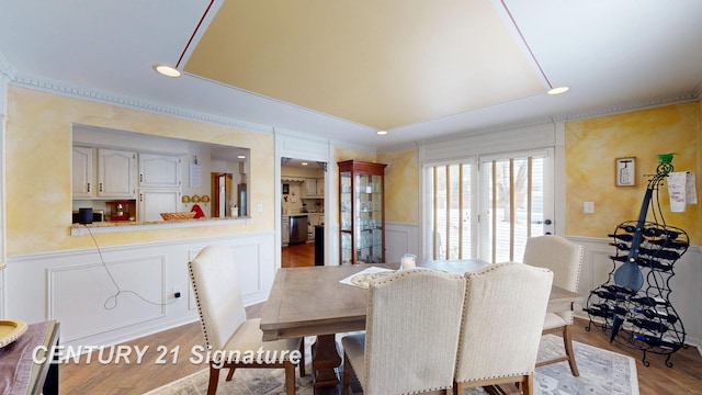 dining area featuring a wainscoted wall, wood finished floors, and a decorative wall