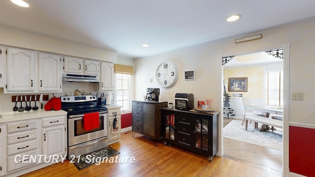 kitchen featuring light wood finished floors, stainless steel electric stove, light countertops, white cabinetry, and under cabinet range hood