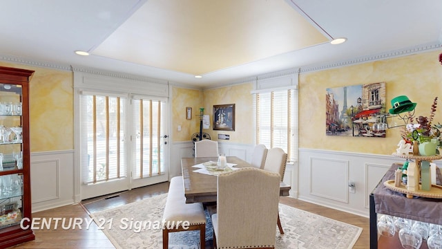 dining space featuring a wainscoted wall, a decorative wall, wood finished floors, and recessed lighting