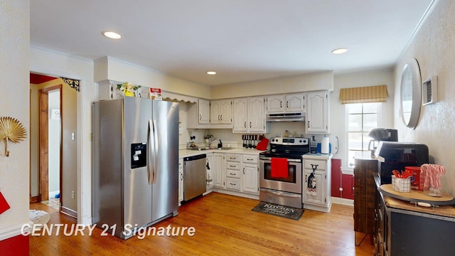 kitchen with recessed lighting, under cabinet range hood, stainless steel appliances, light countertops, and light wood-type flooring