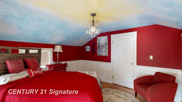 bedroom featuring lofted ceiling, an inviting chandelier, wood finished floors, and wainscoting