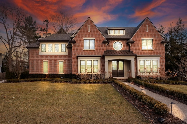 view of front of property featuring brick siding, a front yard, a standing seam roof, and french doors