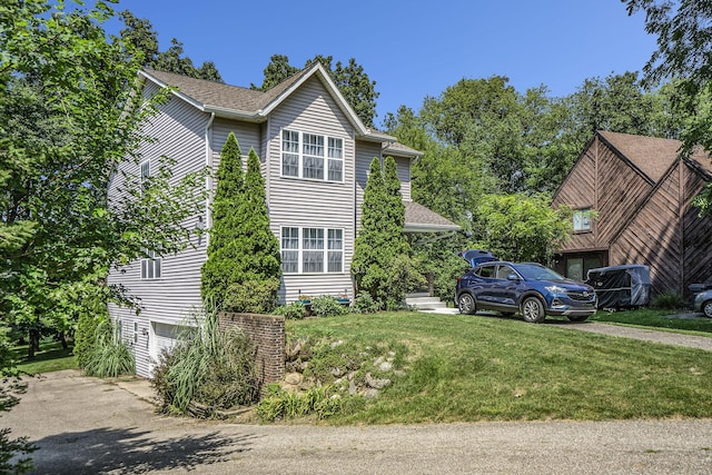 view of front facade featuring driveway, a shingled roof, a garage, and a front lawn