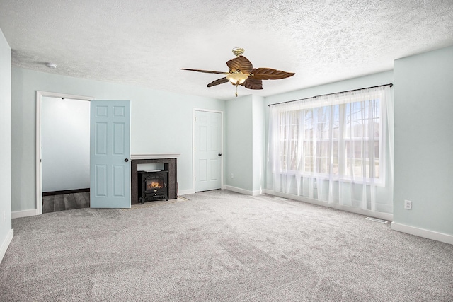 unfurnished living room with visible vents, baseboards, ceiling fan, a textured ceiling, and carpet floors