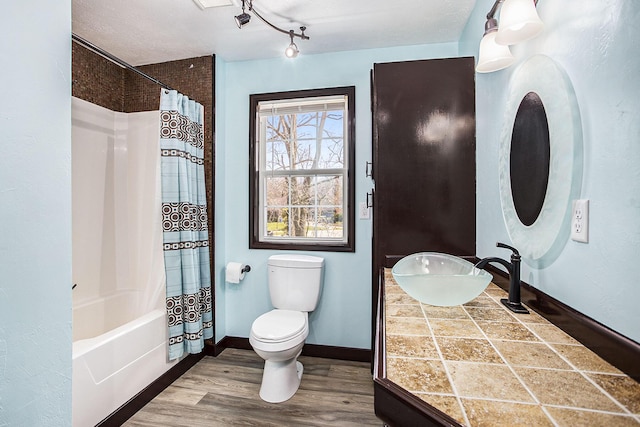 full bathroom with shower / tub combo, baseboards, toilet, wood finished floors, and a sink