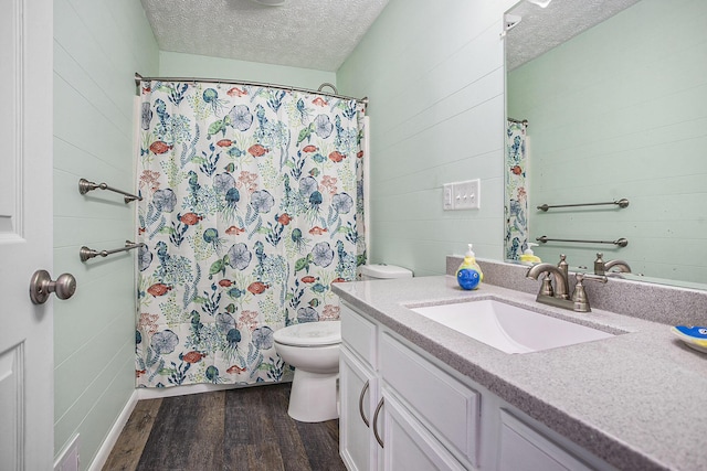 full bath with a textured ceiling, vanity, wood finished floors, and toilet