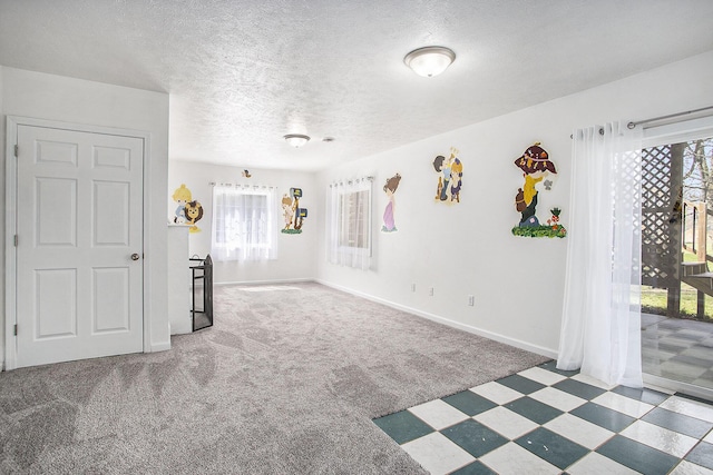 empty room featuring carpet, a textured ceiling, and baseboards