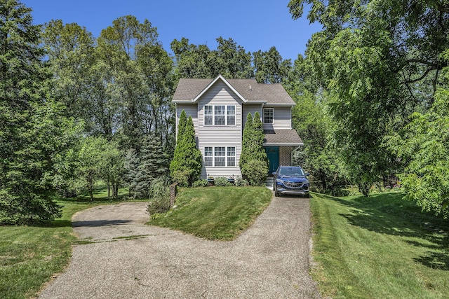 view of front of property with a front yard, roof with shingles, and driveway