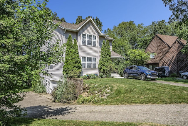 view of front of home featuring a garage, driveway, a front lawn, and roof with shingles