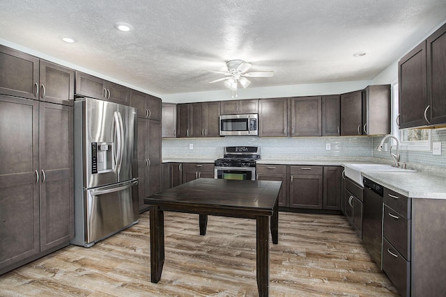 kitchen featuring stainless steel appliances, light wood-style floors, dark brown cabinetry, and a sink