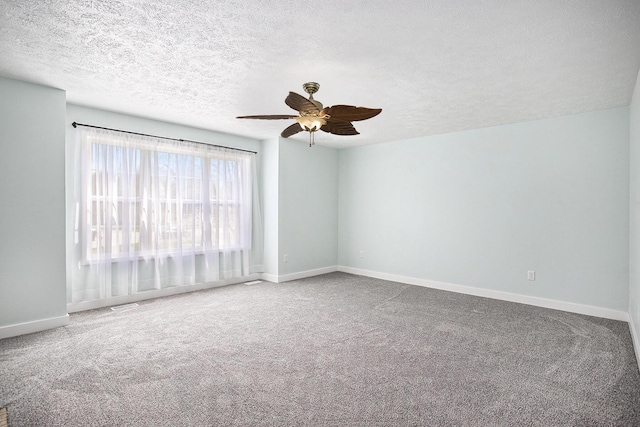 carpeted empty room with ceiling fan, a textured ceiling, and baseboards