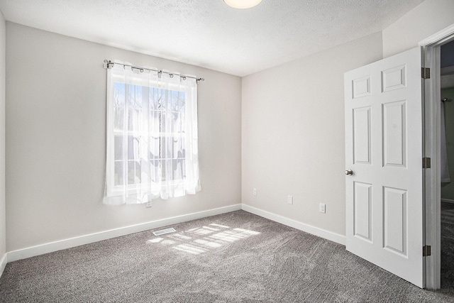 carpeted spare room featuring visible vents, baseboards, and a textured ceiling