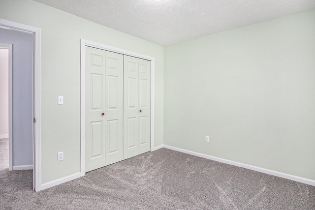 unfurnished bedroom with a textured ceiling, a closet, carpet, and baseboards