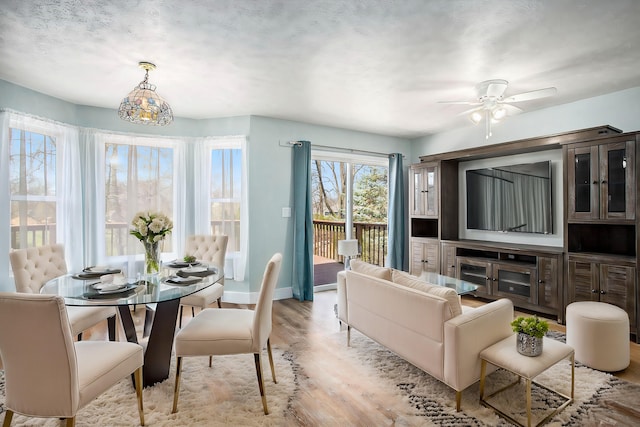 dining space with light wood finished floors, ceiling fan, and baseboards