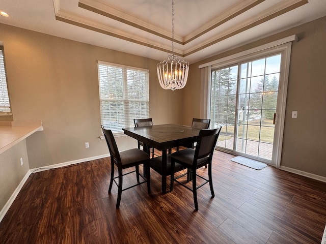 dining room with dark wood-style floors, baseboards, ornamental molding, a raised ceiling, and a notable chandelier