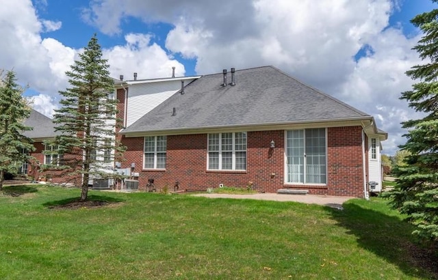back of house featuring brick siding, a lawn, and roof with shingles