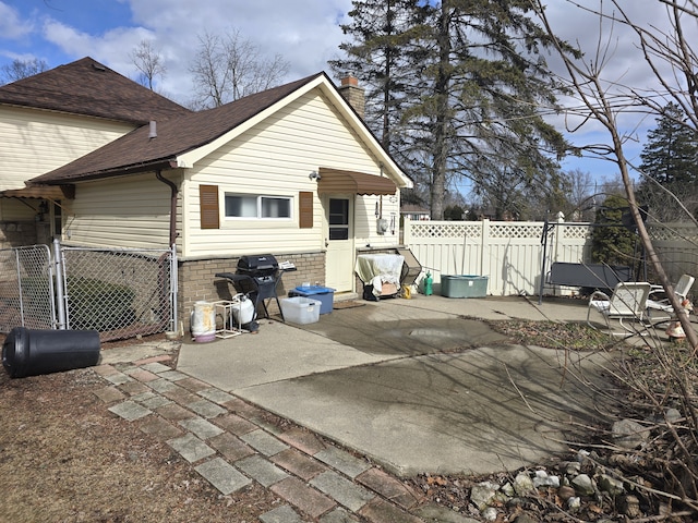 7993 Church Rd, Grosse Ile, MI 48138 - rear view of house with roof with shingles, a chimney, a gate, a patio area, and fence