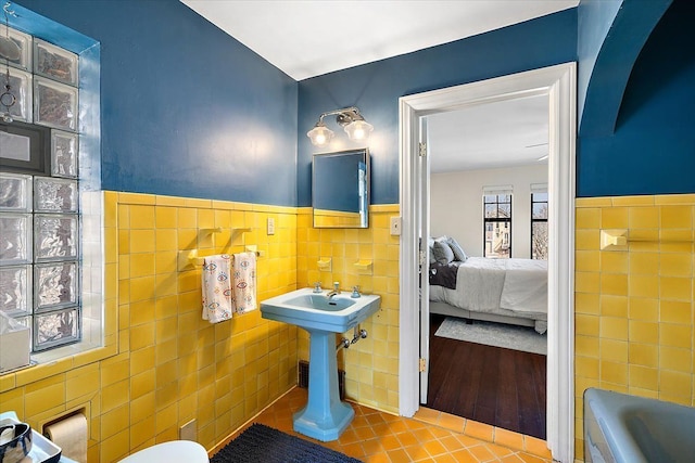 full bathroom featuring tile patterned flooring, wainscoting, tile walls, a bath, and connected bathroom