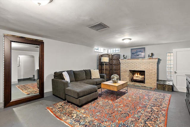 living room with visible vents, arched walkways, concrete flooring, and a fireplace