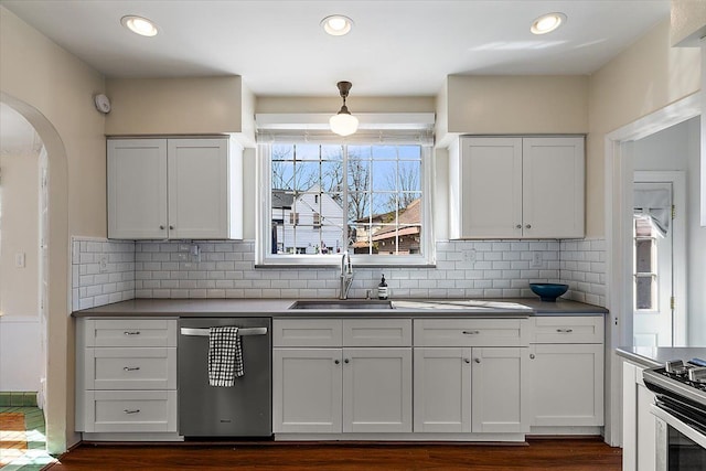 kitchen featuring recessed lighting, arched walkways, a sink, stainless steel appliances, and tasteful backsplash