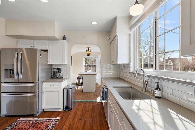 kitchen featuring a sink, stainless steel appliances, arched walkways, and white cabinets