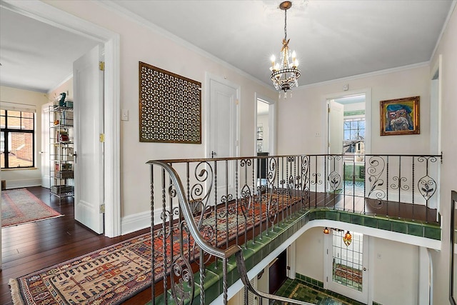 hallway featuring ornamental molding, baseboards, dark wood-style flooring, and a chandelier