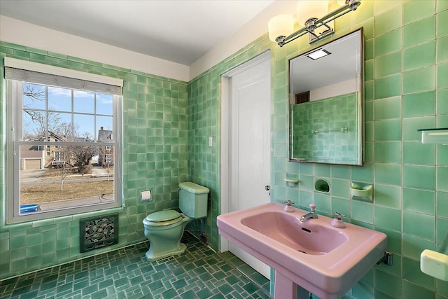 bathroom with tile walls, toilet, and a sink