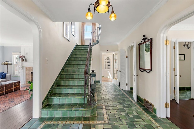 stairway with arched walkways, plenty of natural light, crown molding, and wood finished floors