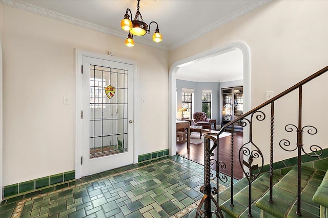 foyer entrance featuring arched walkways, stairway, crown molding, and baseboards