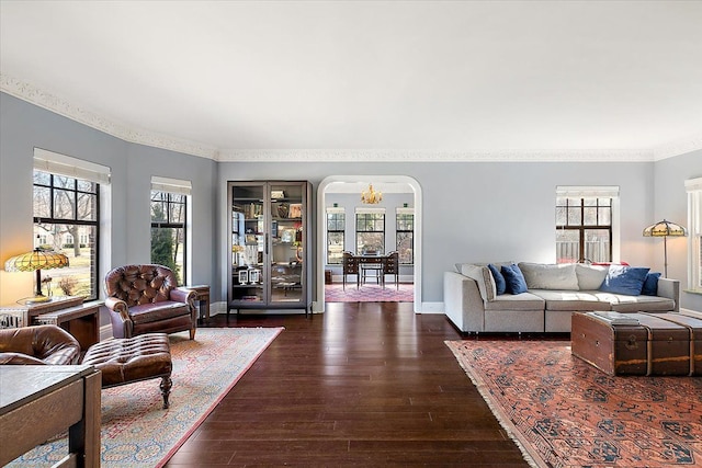 living room featuring arched walkways, ornamental molding, baseboards, and dark wood-style flooring