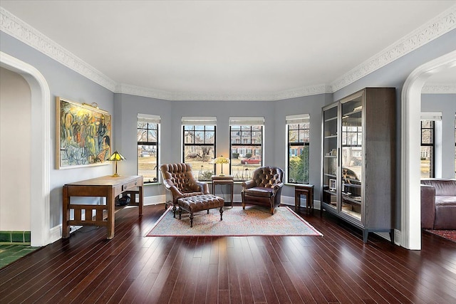 sitting room with arched walkways, plenty of natural light, and hardwood / wood-style flooring