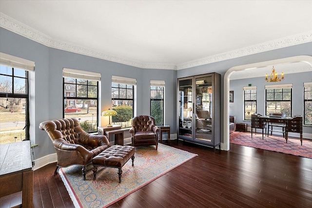 living area featuring baseboards, an inviting chandelier, and dark wood finished floors