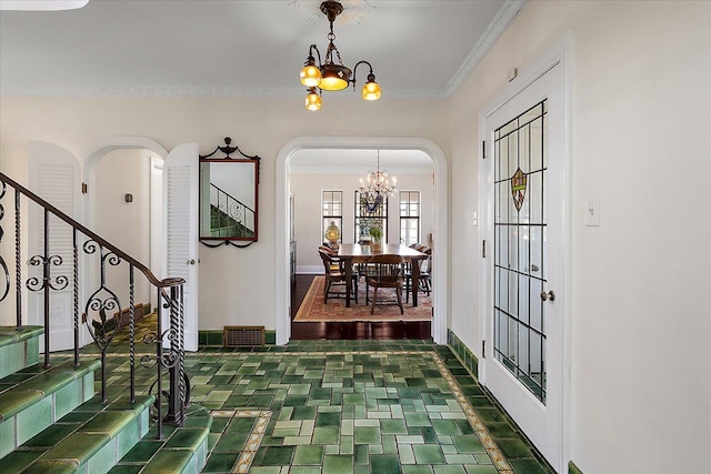 foyer entrance featuring ornamental molding, stairway, arched walkways, baseboards, and a chandelier