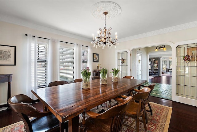 dining room with ornamental molding, dark wood-style floors, arched walkways, and a chandelier