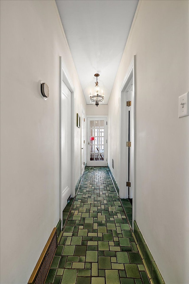 hall with a chandelier, visible vents, and baseboards