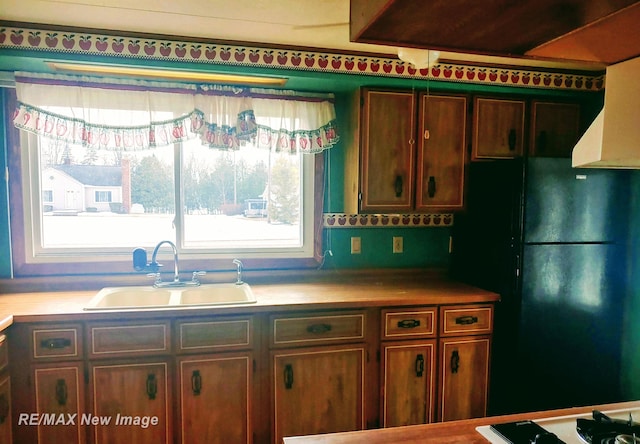 kitchen featuring freestanding refrigerator, light countertops, and a sink