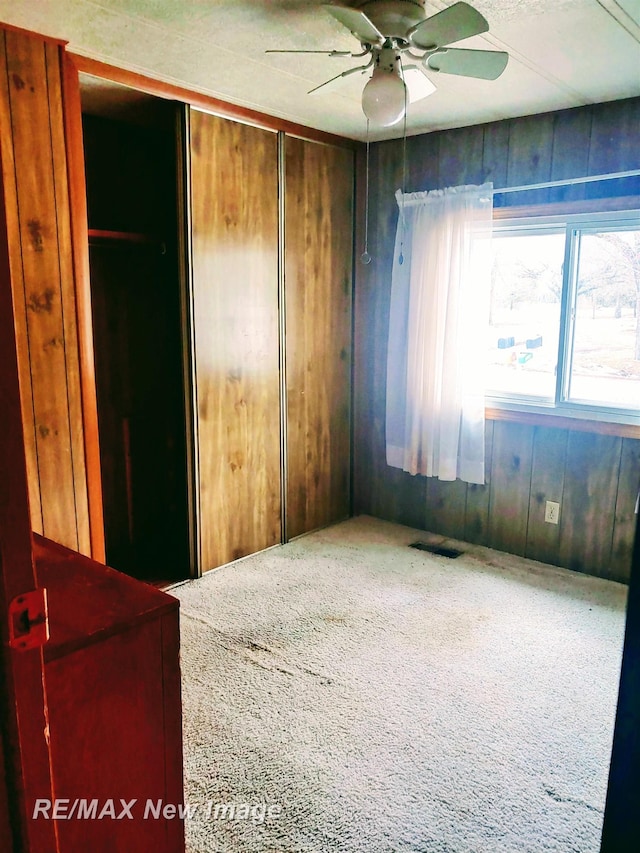 spare room featuring visible vents, ceiling fan, and wooden walls