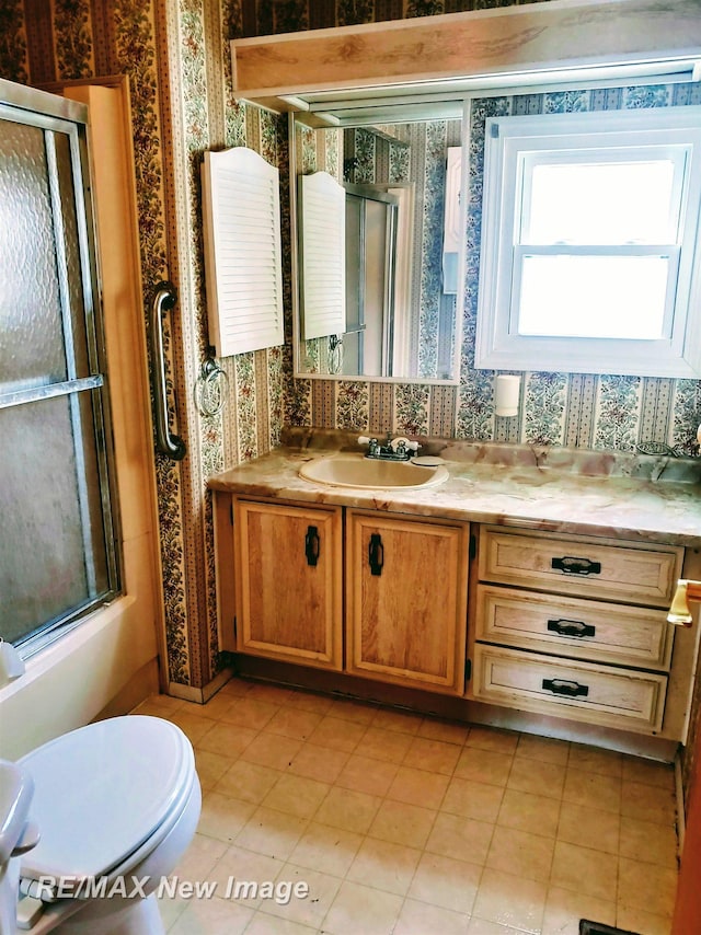 full bath featuring a shower stall, vanity, and wallpapered walls