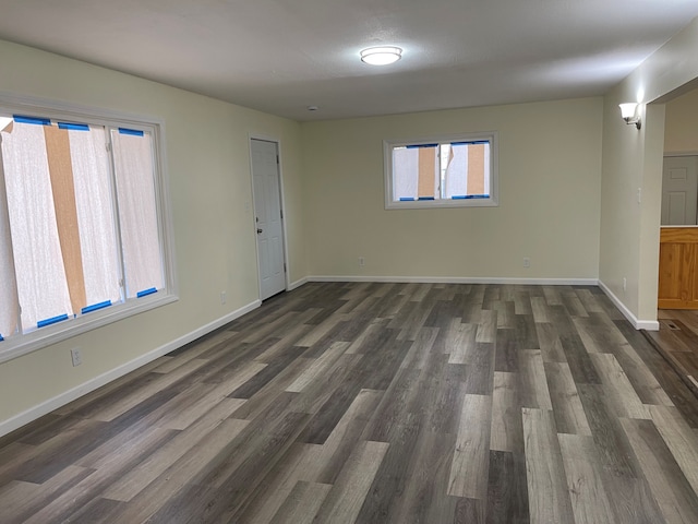 spare room with baseboards and dark wood-style flooring