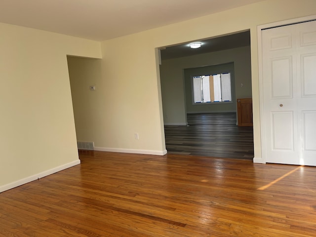 spare room with visible vents, baseboards, and wood finished floors