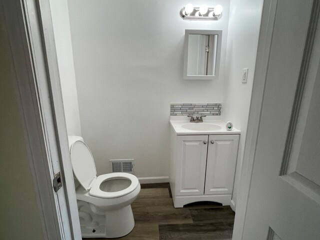 bathroom featuring vanity, wood finished floors, visible vents, toilet, and tasteful backsplash